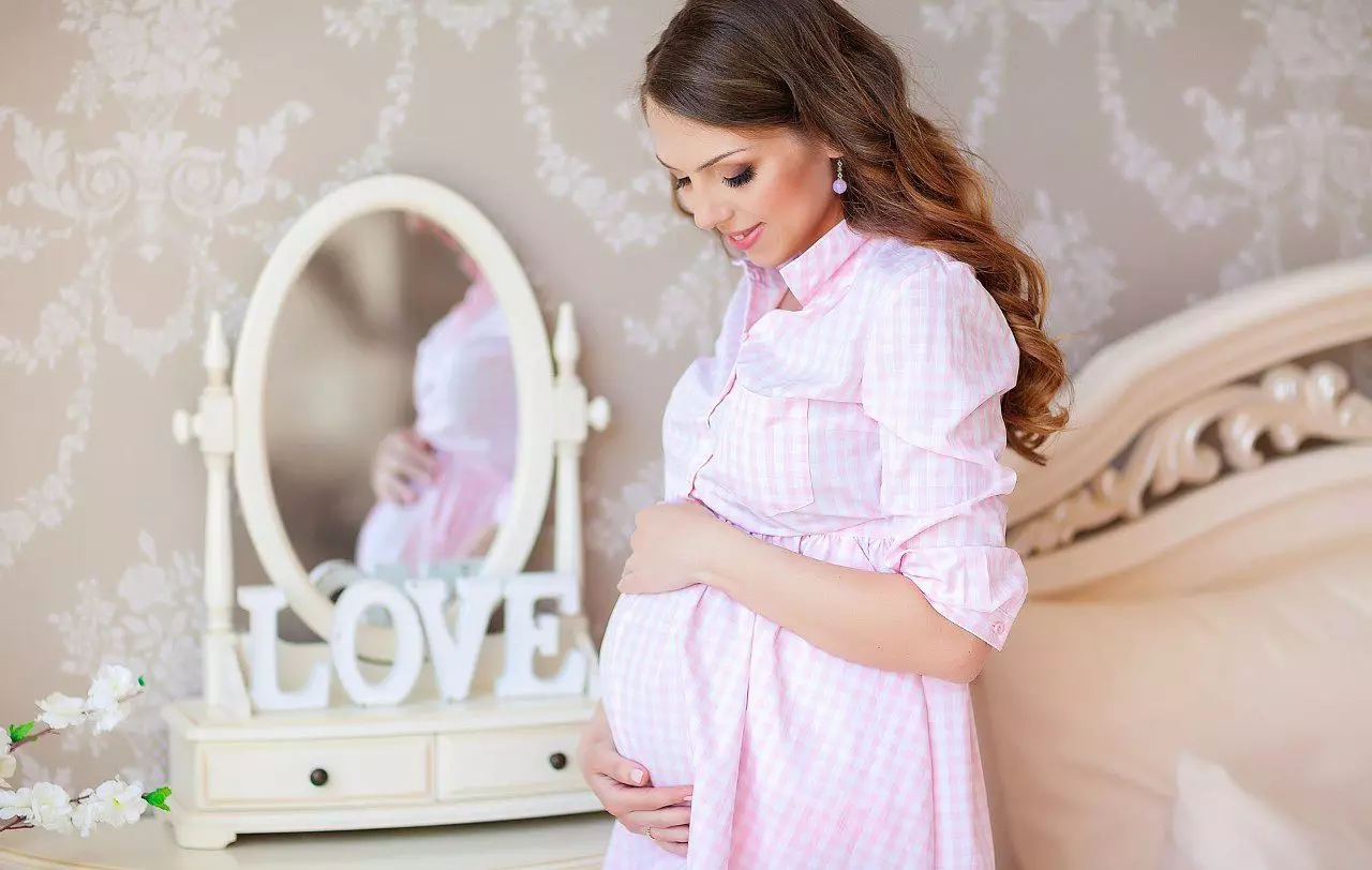 Një sesion foto i një gruaje shtatzënë në një studio foto
