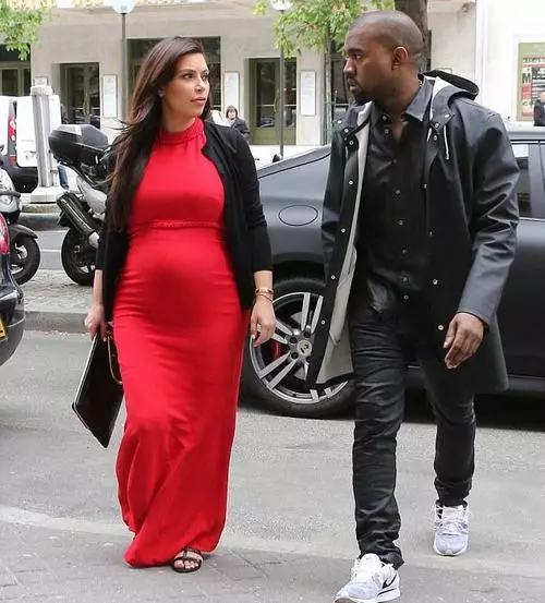 Langes rotes Kleid für schwangere Frauen mit schwarzer Strickjacke und schwarzen Kupplung