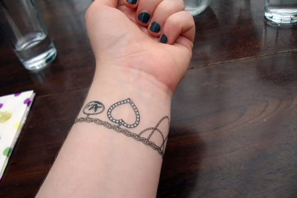 Tatuaggio sotto forma di un braccialetto nelle mani delle ragazze: tatuaggi femminili sul polso e sull'avambraccio, schizzi di fiori tatuaggio sotto forma di un braccialetto e altre opzioni, i loro significati 13770_32