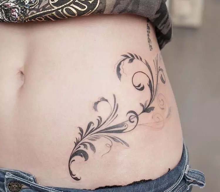 Τατουάζ στο στομάχι (50 φωτογραφίες): Στον ομφαλό, στον τύπο και στην κοιλιά στο κάτω μέρος. Σκίτσα από όμορφα τατουάζ. Τατουάζ στοιχεία 1999 και 2002, 1998 και άλλα, άλλες επιλογές για μικρές και μεγάλες εικόνες 13790_26