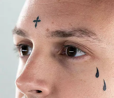 Tatuaxe na cara (57 fotos): Para nenas e homes, bocetos de pequenos tatuaxes e grandes. Tatuaxe na fronte e sobre as cellas, na fazula e noutras partes da cara 13818_31