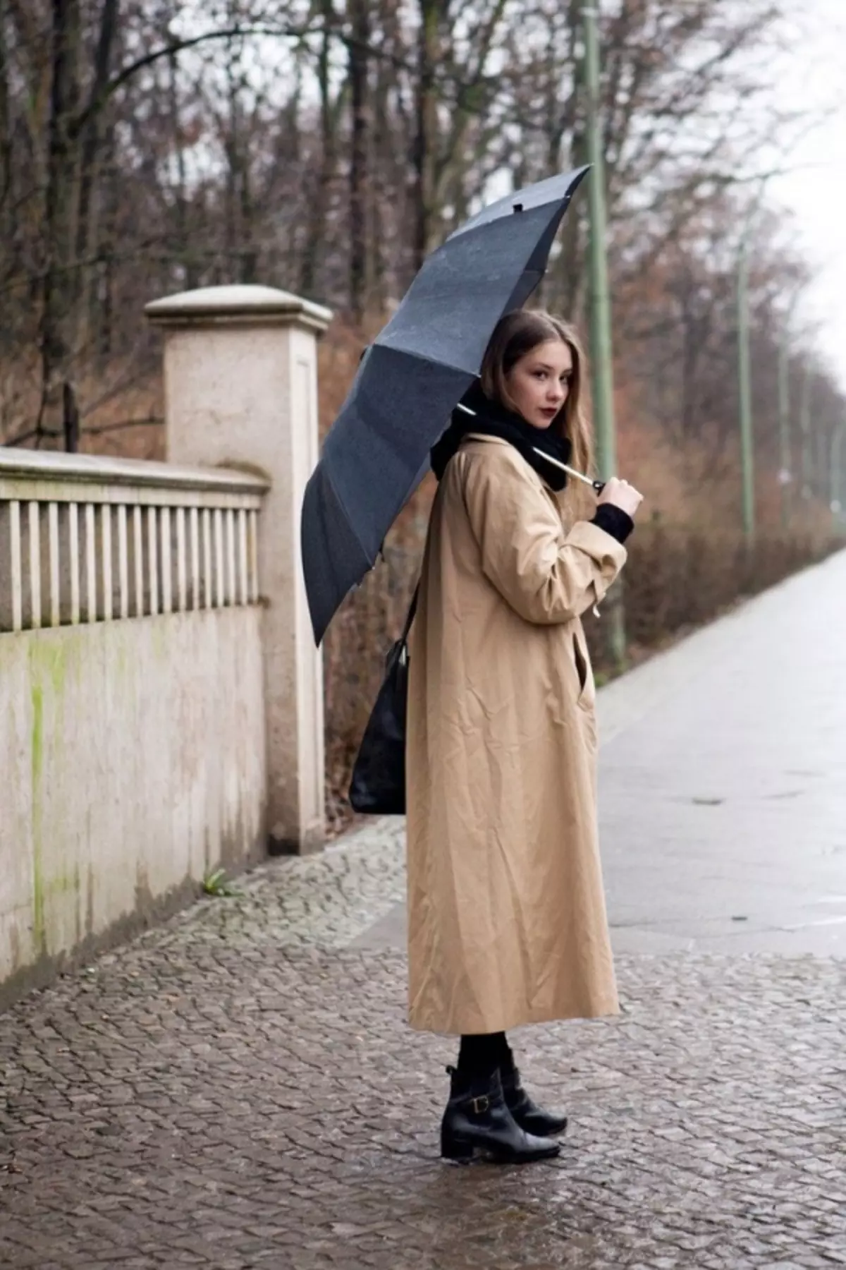 Среди серых еще не одетых деревьев. Женщина в плаще. Женщина в пальто. Красивая девушка в плаще. Пальто и зонт.