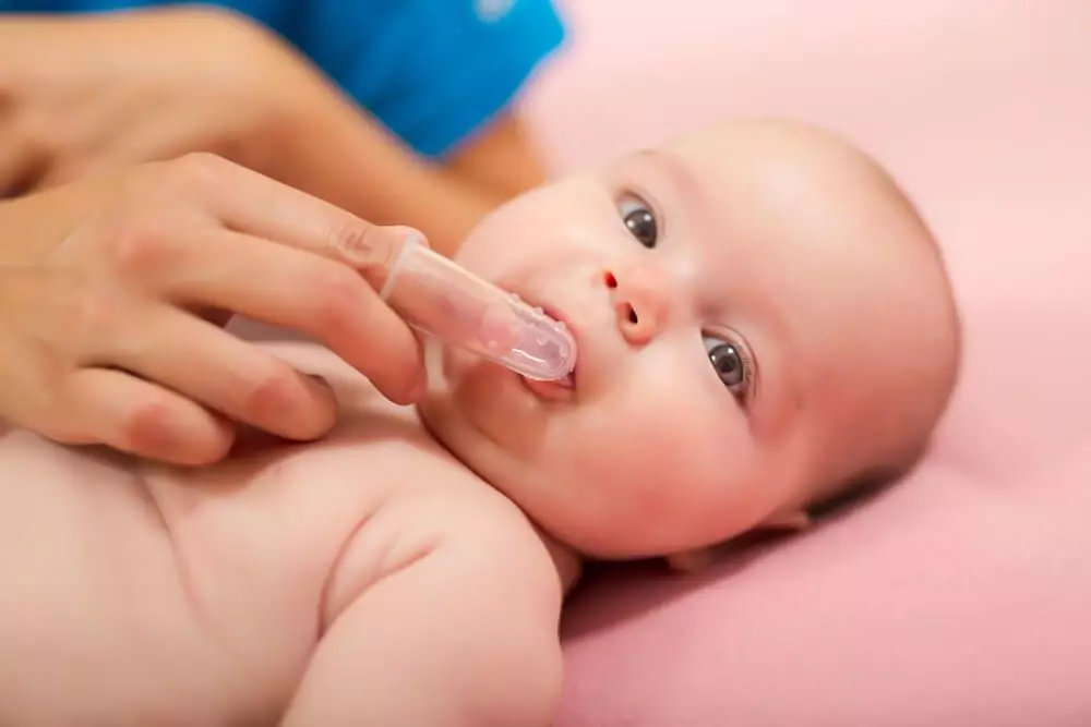 Cando comezar a cepillar os dentes do bebé? Que idade pode acostumar o neno a pasta de dentes adultos? Cantos anos tes que usar un viveiro? 16139_6