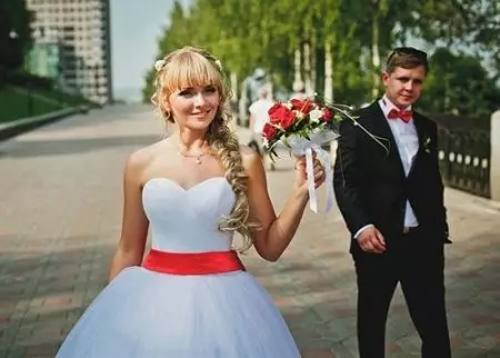 Vestuvių suknelė su raudona juosta ir raudona puokštė
