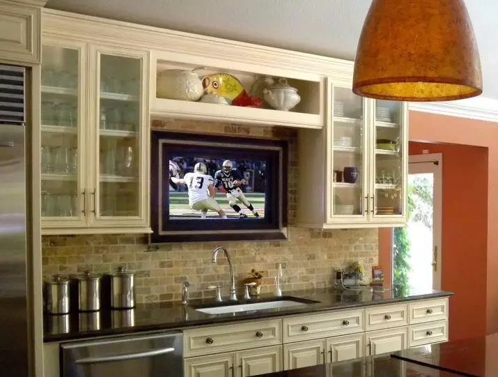Opcions d'allotjament de la televisió de cuina (56 fotos): instal·lació en els auriculars de la cuina, opcions de disseny de cuina. Com penjar la televisió sobre la taula? 20943_2