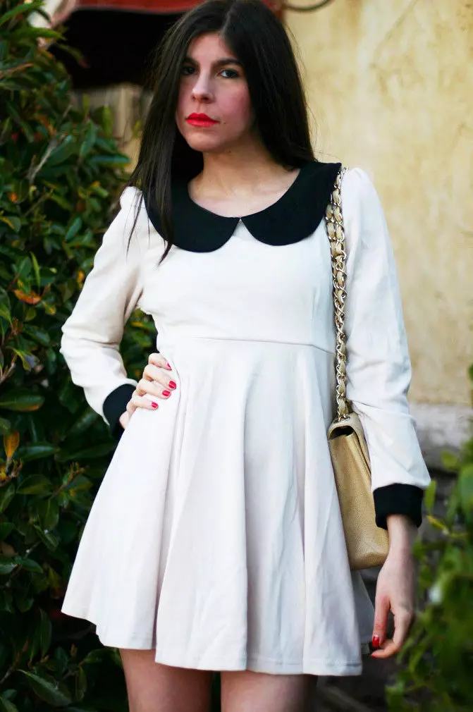 Gebreide witte jurk met een overweldigde taille met een zwarte kraag en manchetten