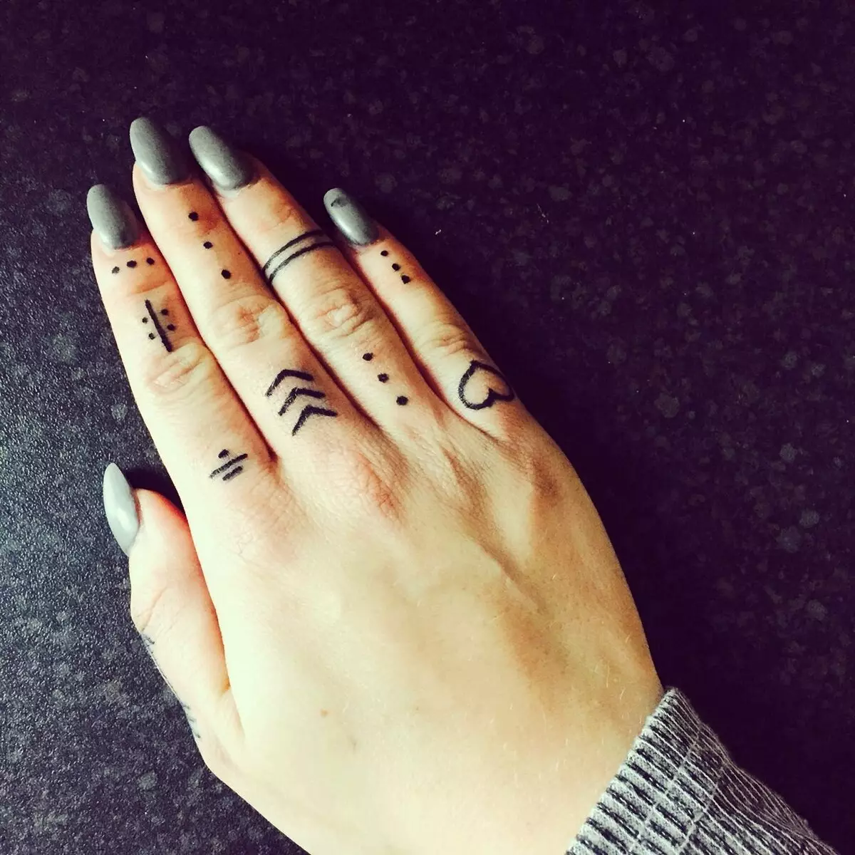 Tattoo op de vingers voor meisjes (68 foto's): vrouwelijke kleine tatoeages en hun schetsen. Mini-tattoo aan de zijkant van de naamloze vinger en op de grote, op de Maizin-kerel en op de andere vingers 247_43