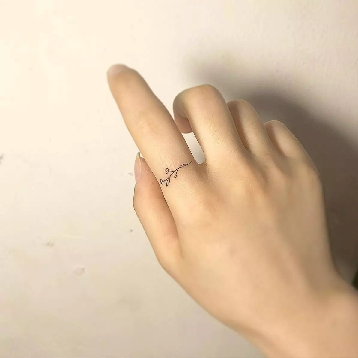 Tatuering på fingrarna för tjejer (68 bilder): kvinnliga små tatueringar och deras skisser. Mini-tatuering på sidan av det namnlösa fingret och på den stora, på Maizin-källan och på de andra fingrarna 247_50