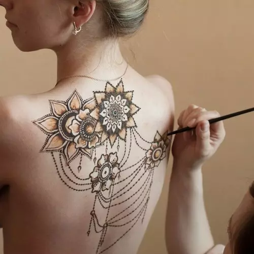Mehendi sul retro (32 foto): Disegni femminili di hennè e uomini, tatuaggio sulla parte superiore della schiena e nella parte bassa della schiena, schizzi leggeri Mehendi sotto forma di ali e altre opzioni 293_20