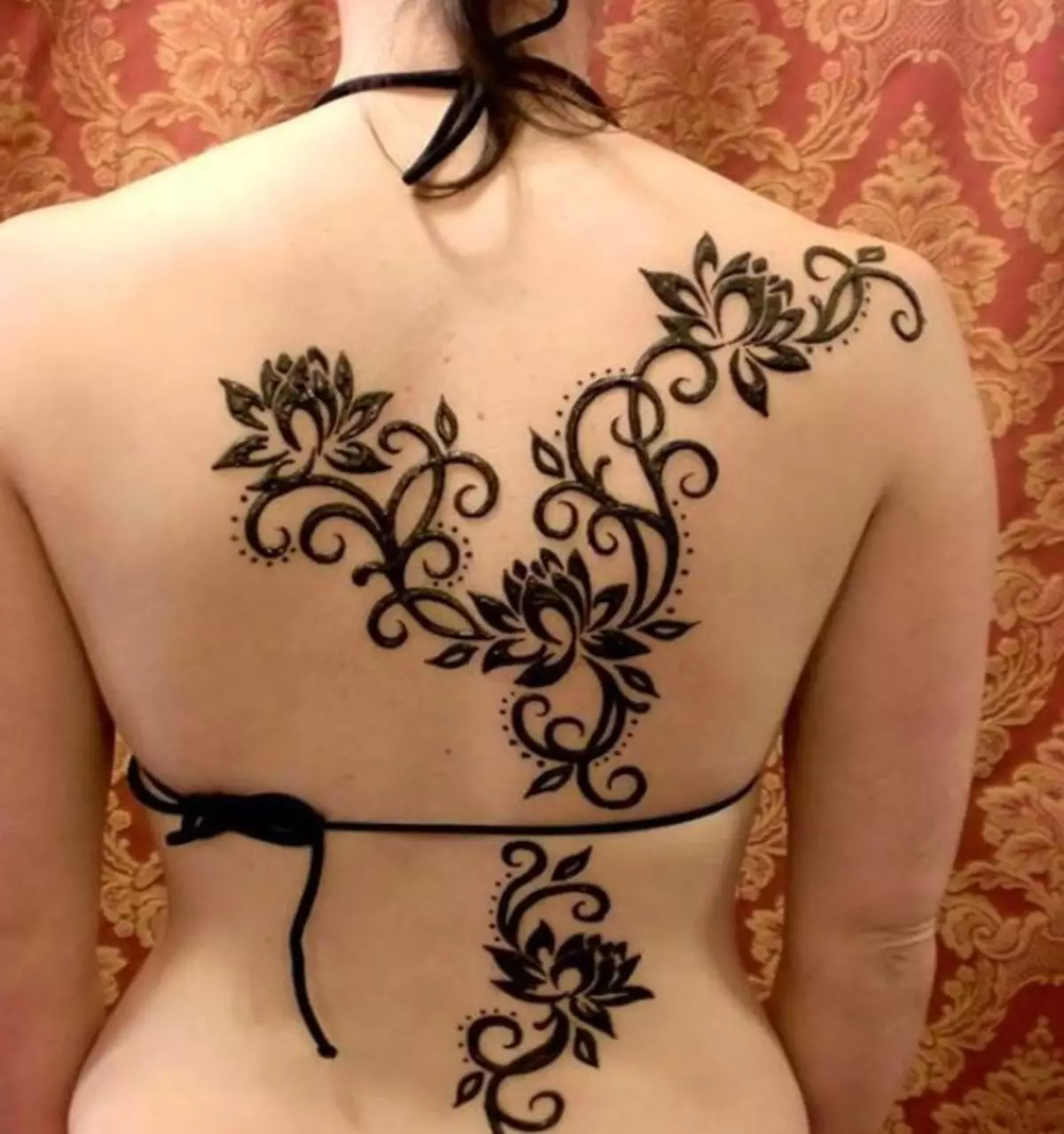 Mehendi sul retro (32 foto): Disegni femminili di hennè e uomini, tatuaggio sulla parte superiore della schiena e nella parte bassa della schiena, schizzi leggeri Mehendi sotto forma di ali e altre opzioni 293_26
