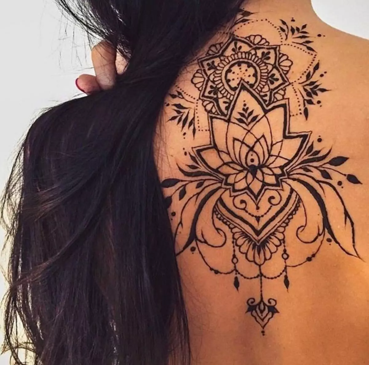 Mehendi sul retro (32 foto): Disegni femminili di hennè e uomini, tatuaggio sulla parte superiore della schiena e nella parte bassa della schiena, schizzi leggeri Mehendi sotto forma di ali e altre opzioni 293_9