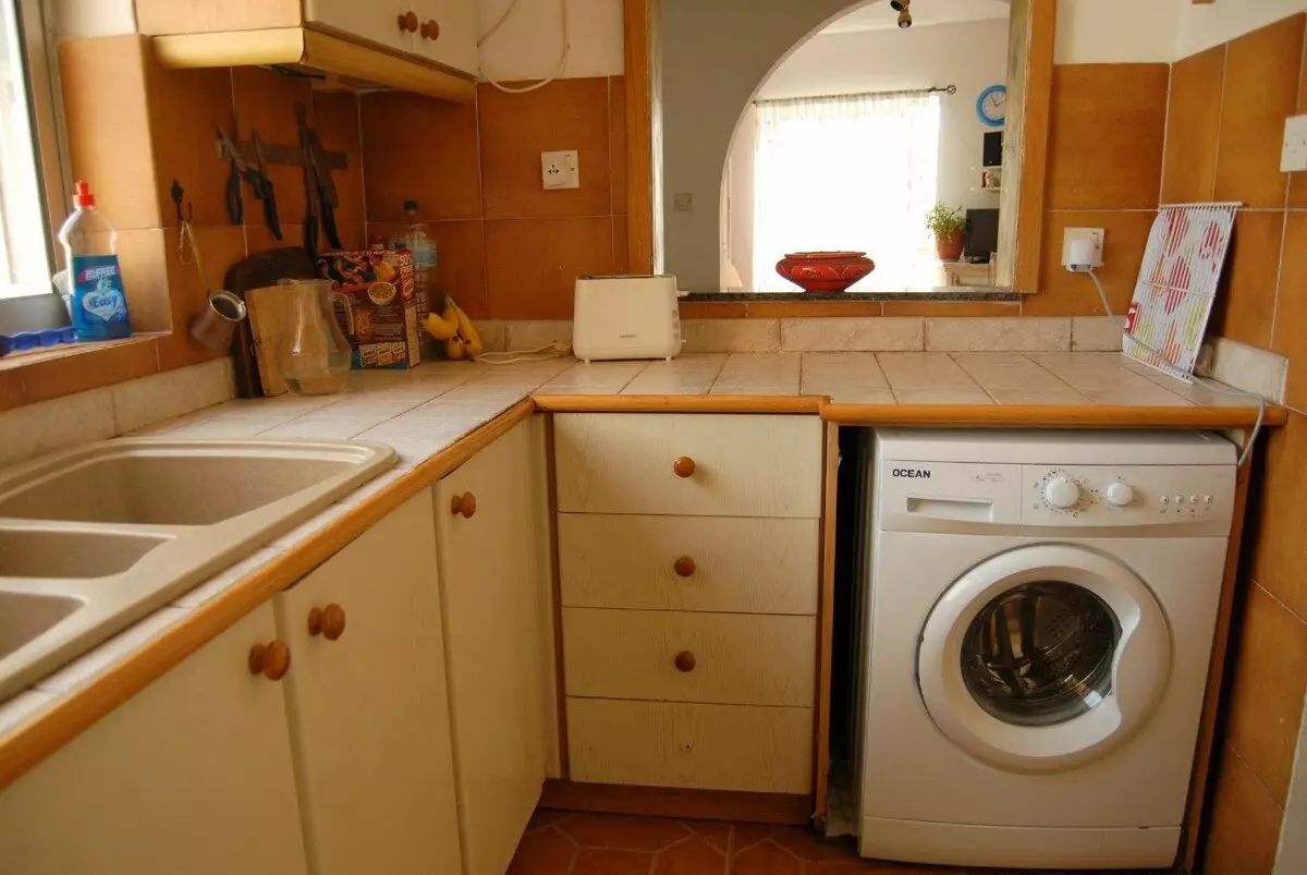 Dapur dengan mesin basuh (45 foto): Mesin di bawah meja atas dan di alat dengar dapur sudut. Bagaimana untuk menyembunyikan kereta di bahagian dalam dapur kecil dengan peti sejuk? 9419_3