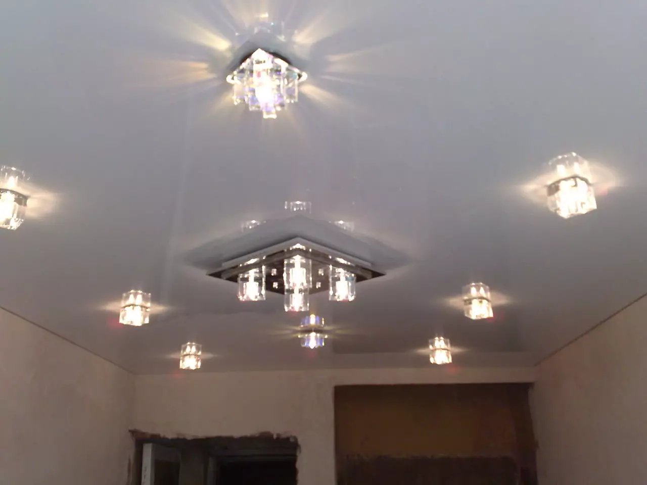 Het aansteken van de spanplafond in de hal (61 foto's): Hoe lampen te vinden voor het benadrukken in de woonkamer zonder een kroonluchter? Kenmerken van punt verlichting, opties voor de locatie van de LED-lampen 9617_31